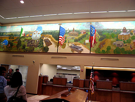 As you enter the First National Bank Lobby, you will see a view of the bank teller department and a partial view of the central panel of the Bastrop History Mural.
