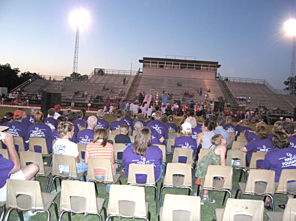 Survivors assemble in chairs on the field