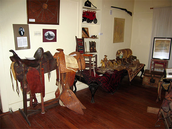 Early Saddles and Model of Ox drawn covered wagon in the Western Room.